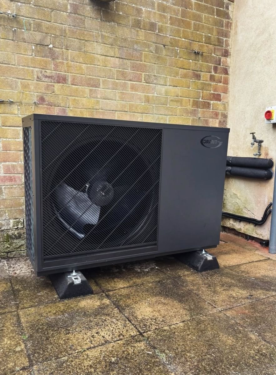 Black Grant air source heat pump on a paved yard