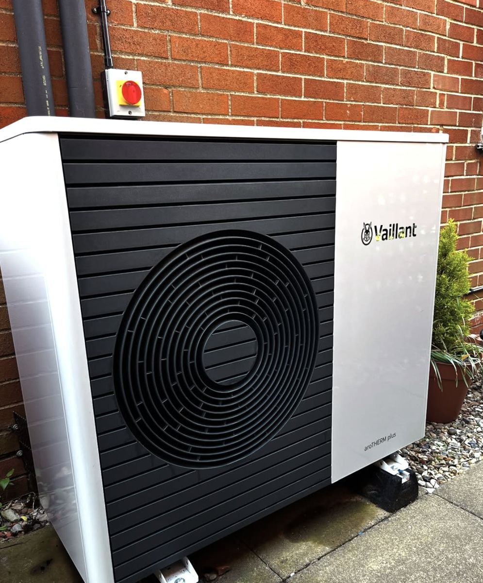 Vaillant aroTHERM plus beside a red brick wall with isolator switch