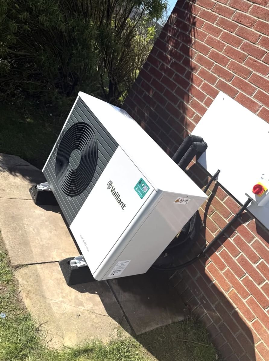 Vaillant heat pump with insulated pipework and isolator on a brick wall